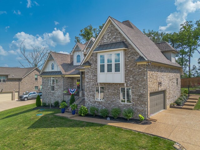 view of front of house with a shingled roof, concrete driveway, a standing seam roof, a front lawn, and brick siding