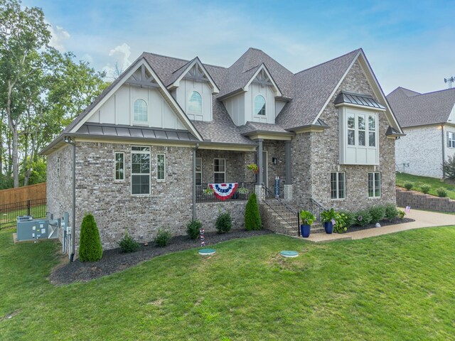 view of front of property with a shingled roof, a front lawn, board and batten siding, and brick siding