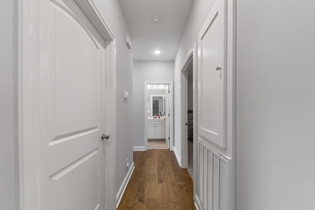 corridor featuring dark wood-type flooring, visible vents, and baseboards