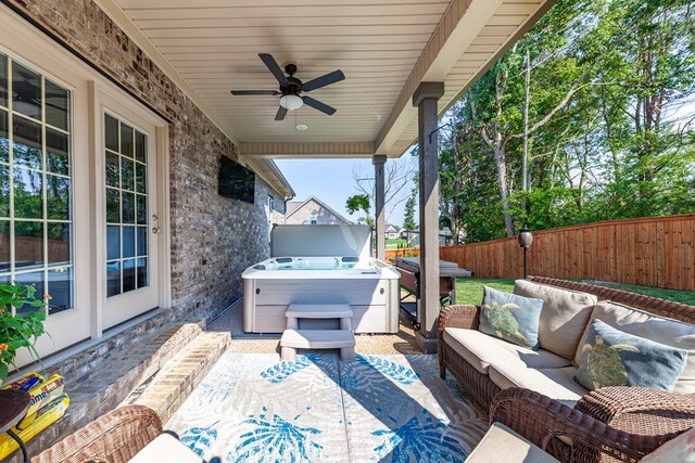 view of patio featuring a hot tub, a ceiling fan, an outdoor living space, and a fenced backyard