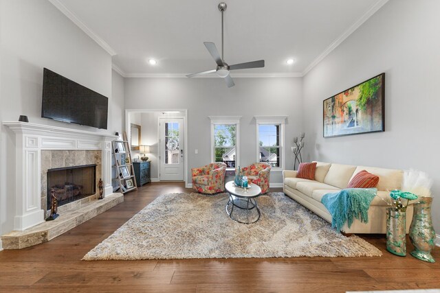 living room with recessed lighting, dark wood-type flooring, a fireplace, a ceiling fan, and crown molding