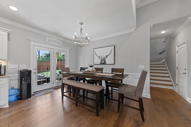 dining space featuring a notable chandelier, dark wood-style flooring, ornamental molding, stairway, and wainscoting