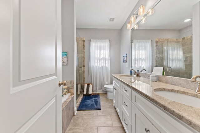 bathroom featuring toilet, double vanity, a sink, and visible vents