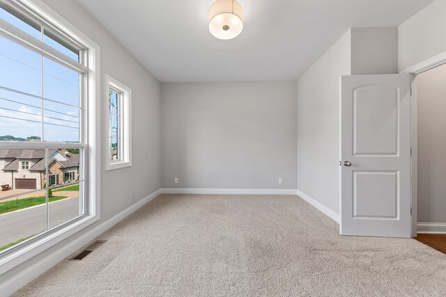 spare room with baseboards, visible vents, and light colored carpet