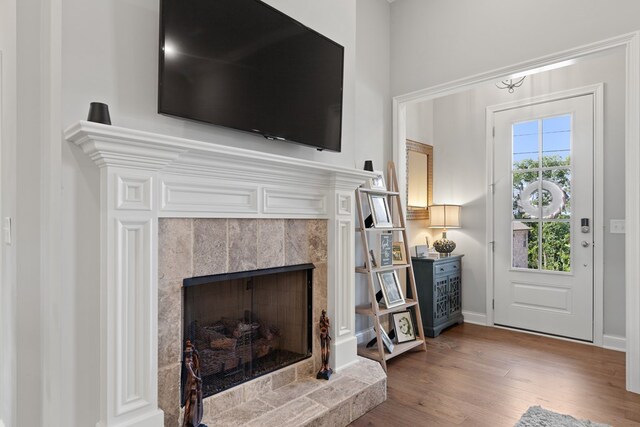 interior space featuring a tiled fireplace, baseboards, and wood finished floors