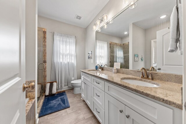 full bathroom featuring double vanity, a stall shower, a sink, and visible vents