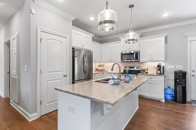 kitchen featuring a center island with sink, light stone countertops, stainless steel appliances, white cabinetry, and pendant lighting