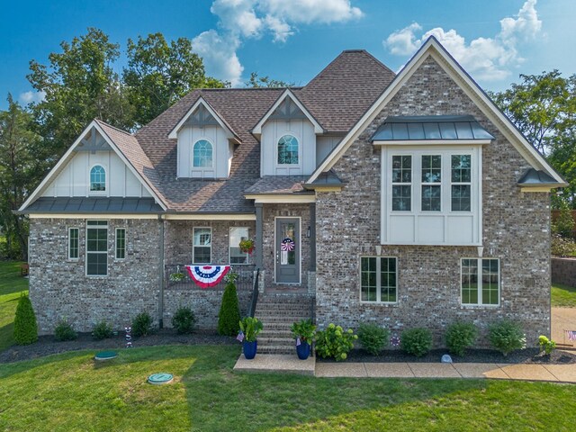 craftsman-style house featuring metal roof, brick siding, roof with shingles, a front lawn, and a standing seam roof