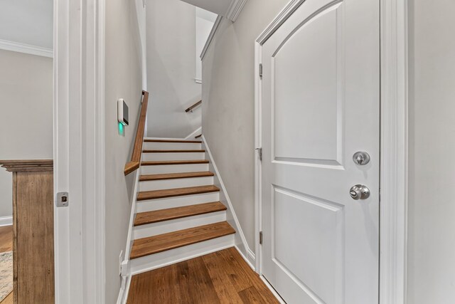 stairs featuring crown molding and wood finished floors