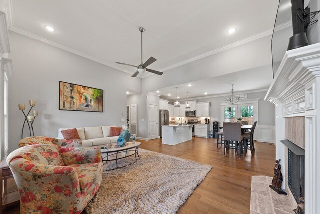 living area with ceiling fan, ornamental molding, a high end fireplace, and light wood-style flooring