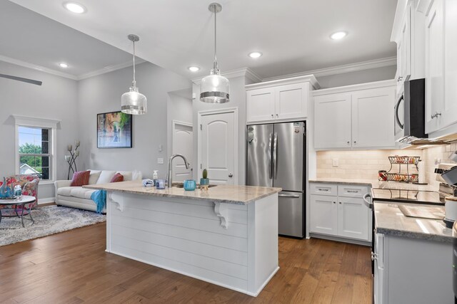 kitchen with stainless steel appliances, white cabinetry, open floor plan, an island with sink, and decorative light fixtures