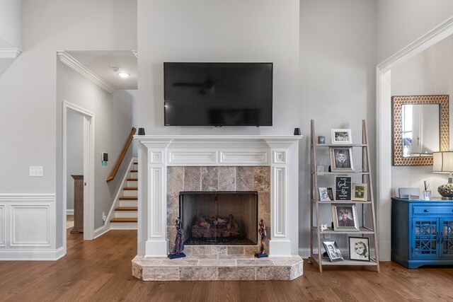 unfurnished living room featuring crown molding, stairway, wood finished floors, a tile fireplace, and baseboards