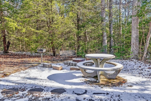 snow covered patio with a forest view