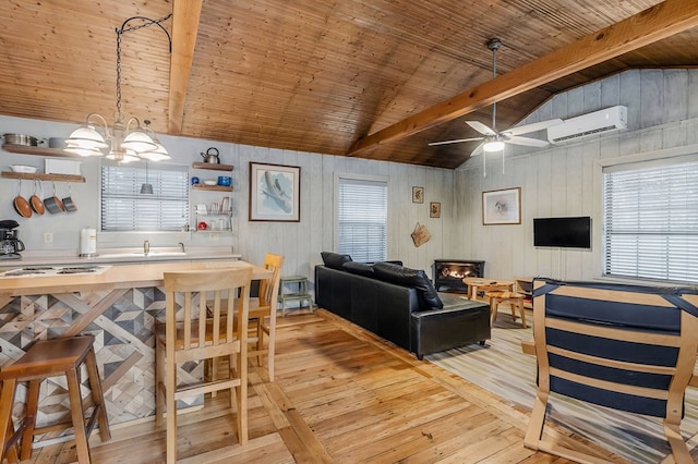 living room featuring a healthy amount of sunlight, light wood finished floors, vaulted ceiling with beams, and a wall mounted air conditioner