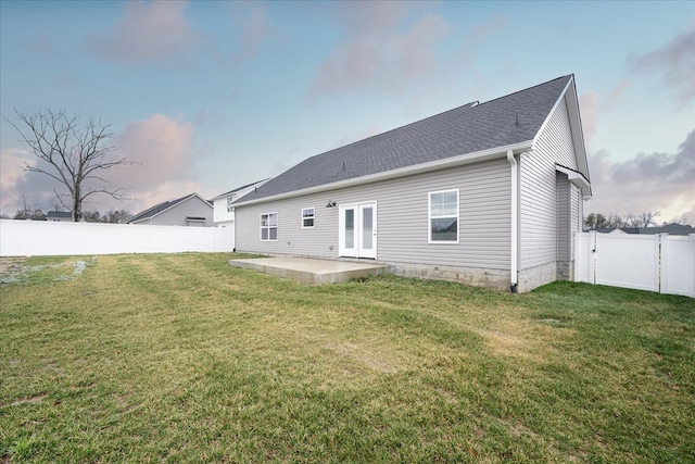 back of house featuring a patio, roof with shingles, a yard, a fenced backyard, and french doors