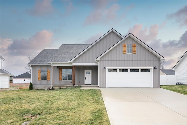 view of front facade with an attached garage, driveway, a shingled roof, and a front lawn