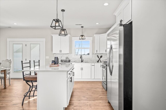 kitchen with a sink, a kitchen breakfast bar, tasteful backsplash, a center island, and appliances with stainless steel finishes