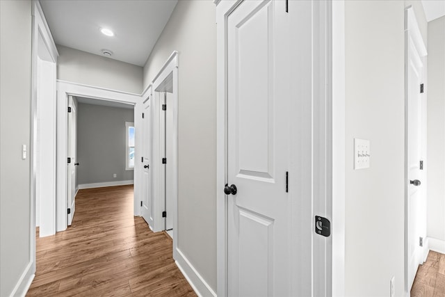 corridor with baseboards and light wood-style flooring