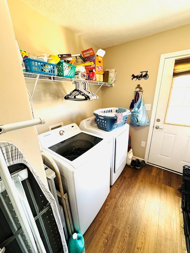 laundry area featuring a textured ceiling, wood finished floors, washer and dryer, laundry area, and baseboards