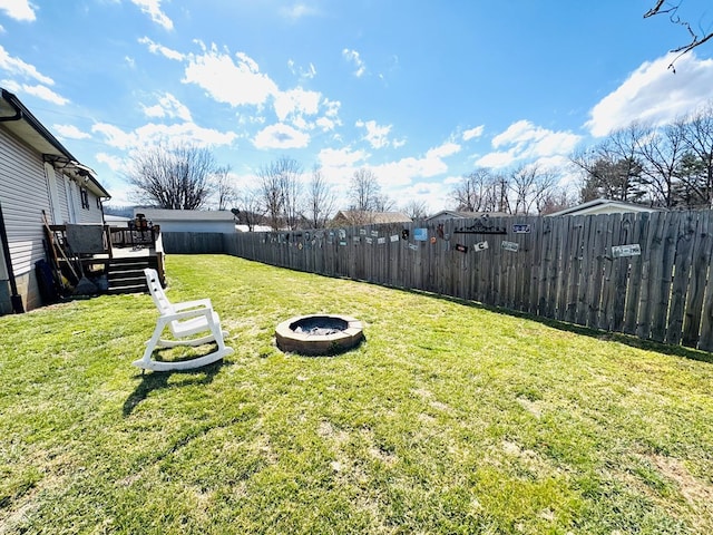 view of yard featuring a fenced backyard, a fire pit, and a wooden deck