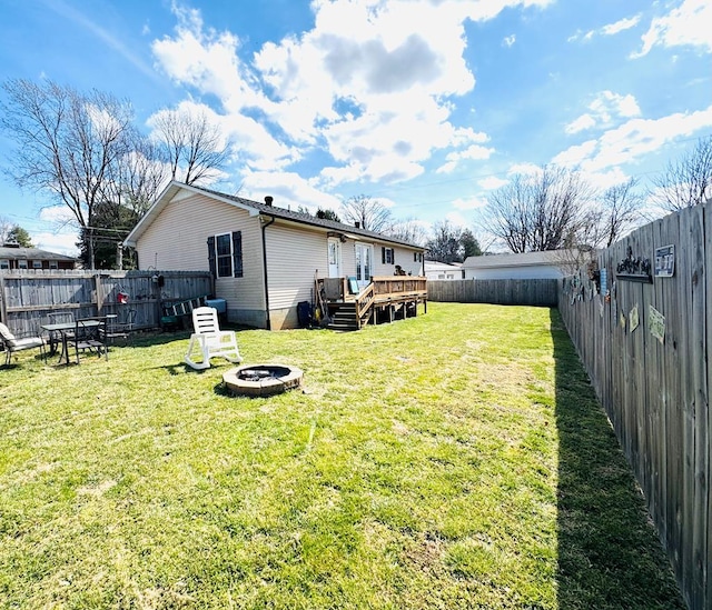 view of yard featuring a fire pit, a fenced backyard, and a wooden deck