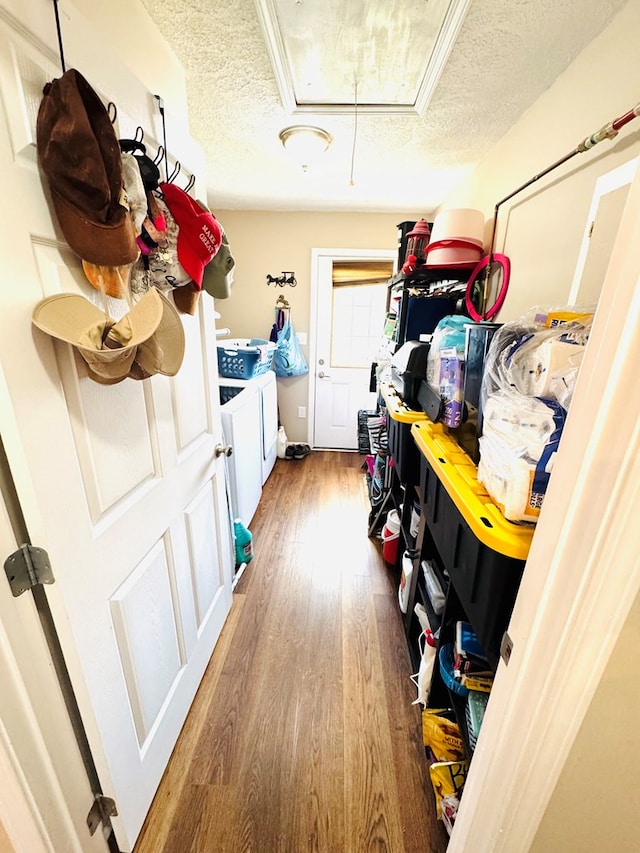 mudroom featuring attic access, washer and dryer, a textured ceiling, and wood finished floors