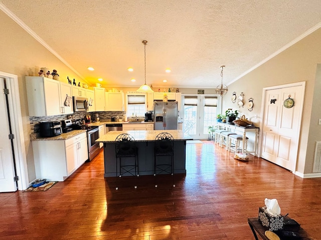 kitchen with lofted ceiling, stainless steel appliances, a kitchen island, and crown molding