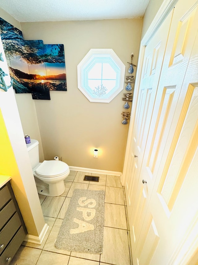 bathroom with baseboards, visible vents, toilet, tile patterned floors, and vanity