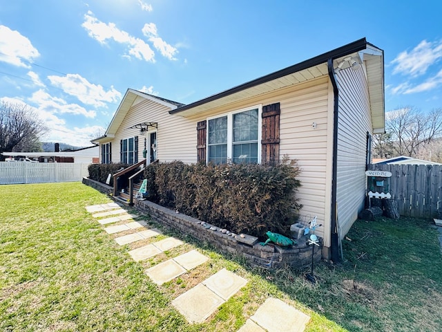 view of property exterior featuring a lawn and fence