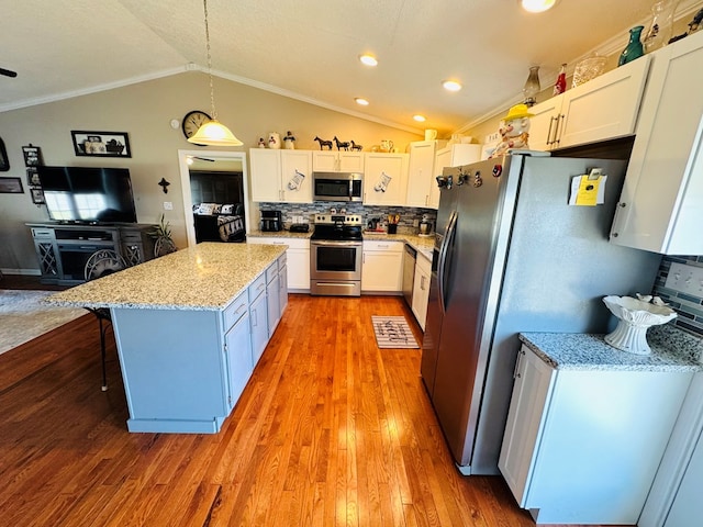 kitchen with stainless steel appliances, a kitchen island, white cabinetry, vaulted ceiling, and decorative backsplash