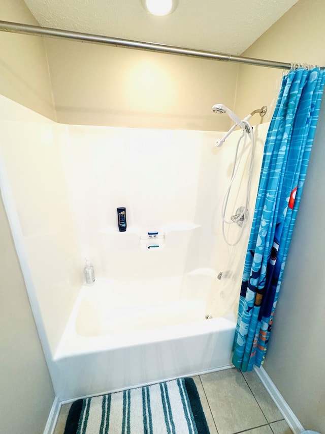 bathroom featuring tile patterned flooring, baseboards, and shower / bath combo with shower curtain