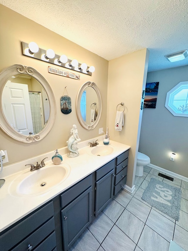 bathroom with a textured ceiling, a sink, and visible vents