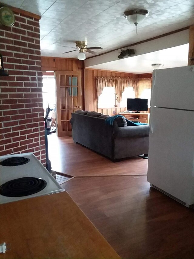 living room featuring a ceiling fan, plenty of natural light, brick wall, and wood finished floors