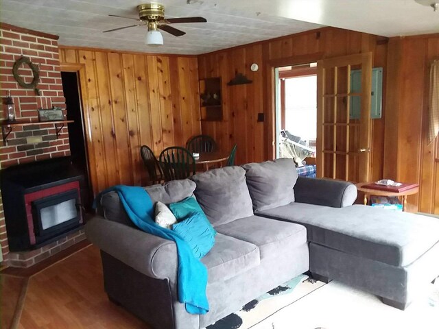 living room with a ceiling fan, dark wood finished floors, and wooden walls