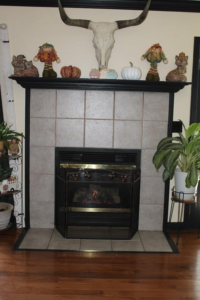 interior details with wood finished floors and a tile fireplace