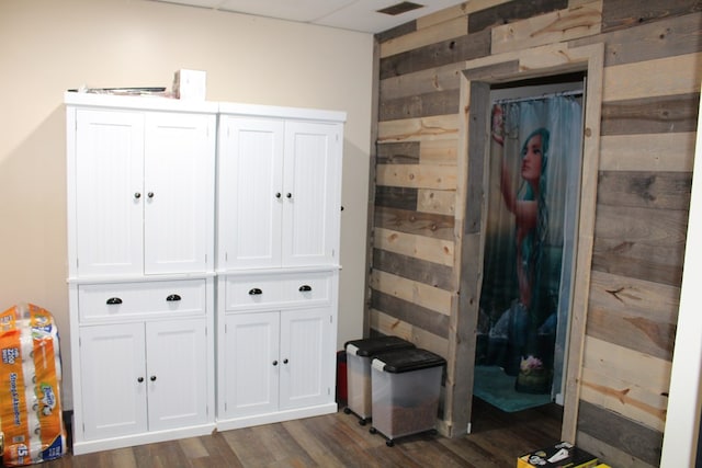 bedroom featuring dark wood-type flooring, visible vents, and wooden walls