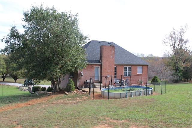 rear view of property with brick siding, a lawn, and roof with shingles