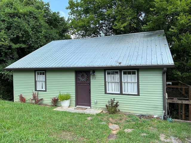 view of front of house featuring metal roof and a front yard