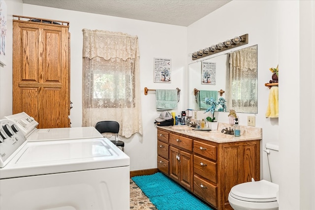 full bath with a textured ceiling, a garden tub, toilet, vanity, and washing machine and clothes dryer