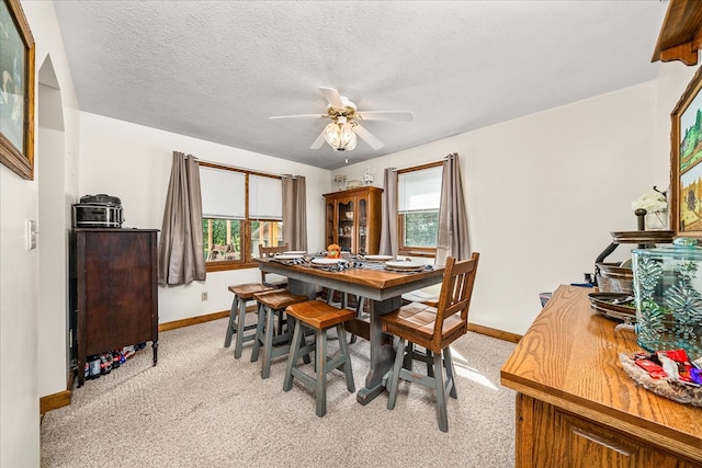 dining room with light carpet, a textured ceiling, a ceiling fan, and baseboards