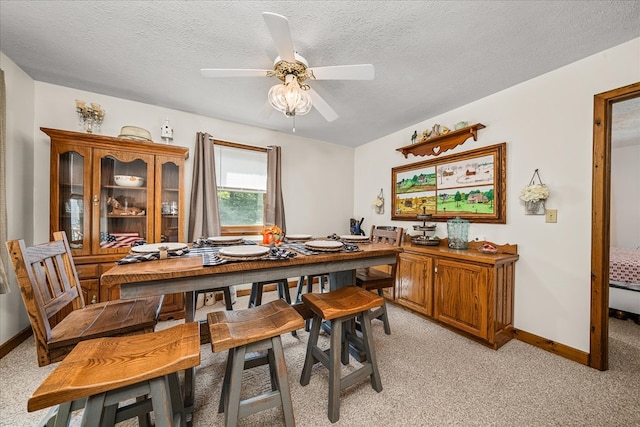 dining space with light carpet, a textured ceiling, and baseboards