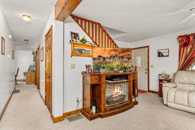 hall with light carpet, baseboards, visible vents, and a textured ceiling