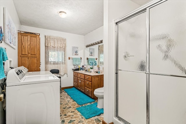 bathroom with toilet, a stall shower, vanity, a textured ceiling, and separate washer and dryer