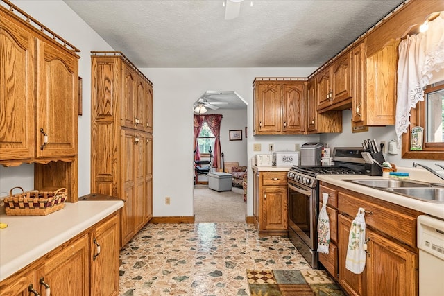 kitchen with a sink, a ceiling fan, light countertops, dishwasher, and gas stove