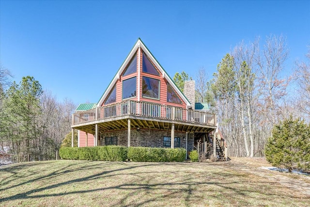 view of front of property with a deck, stairs, stone siding, a chimney, and a front yard