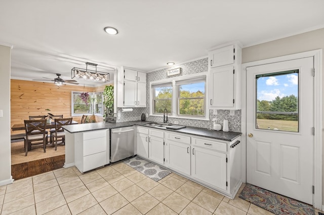 kitchen featuring decorative backsplash, white cabinets, dishwasher, dark countertops, and a sink