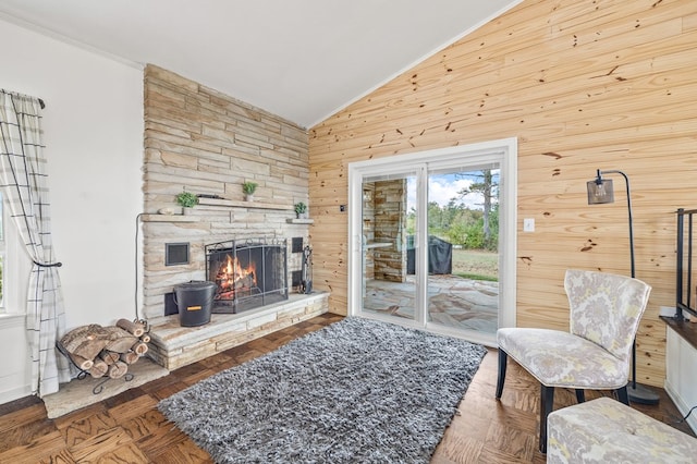 living room featuring vaulted ceiling, a stone fireplace, wood walls, and visible vents