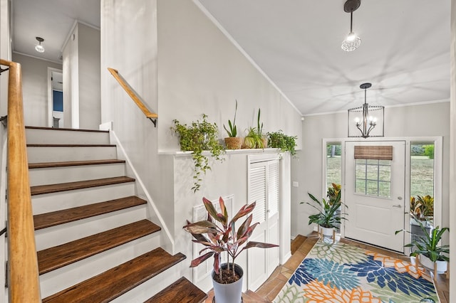 foyer entrance with stairs, ornamental molding, and a chandelier