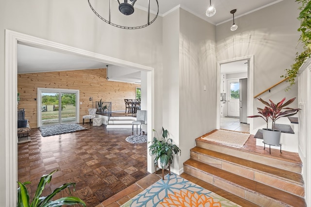 entrance foyer with a towering ceiling, wood walls, a healthy amount of sunlight, and ornamental molding