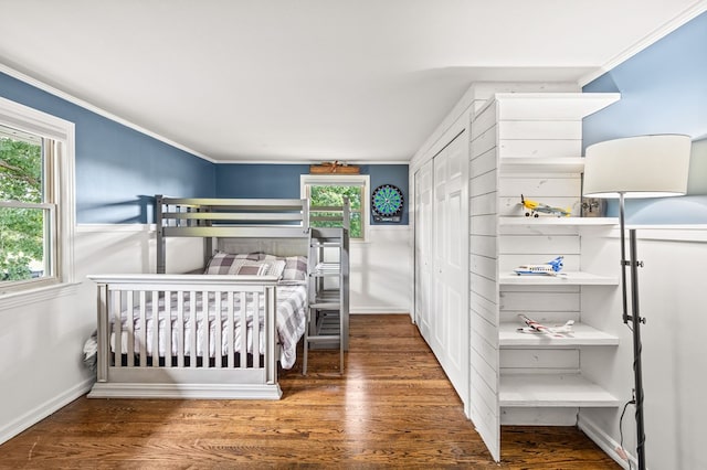 bedroom with dark wood-style floors, ornamental molding, a closet, and baseboards